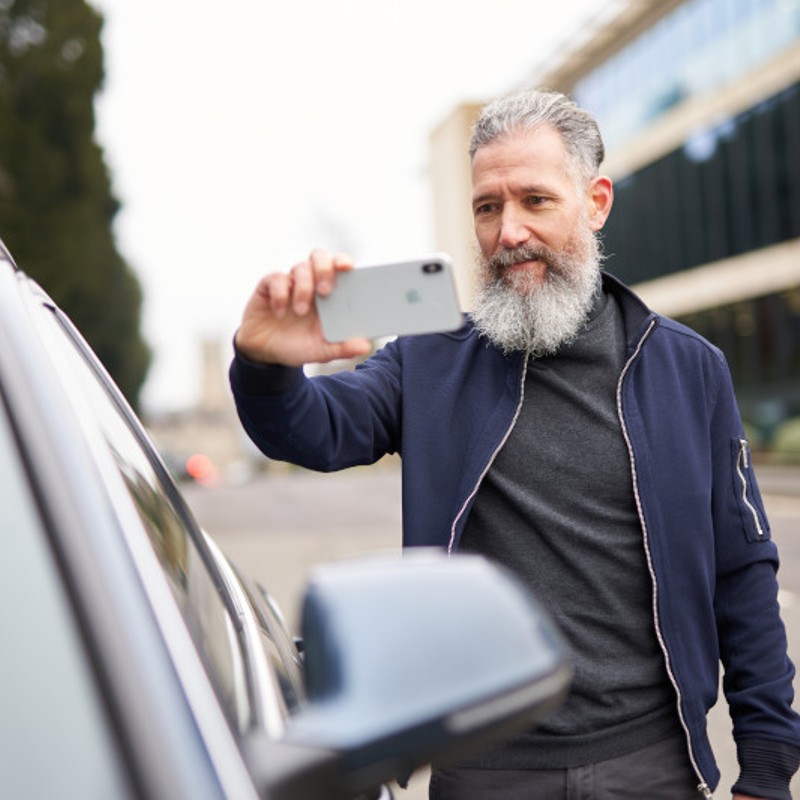 man taking photo of car