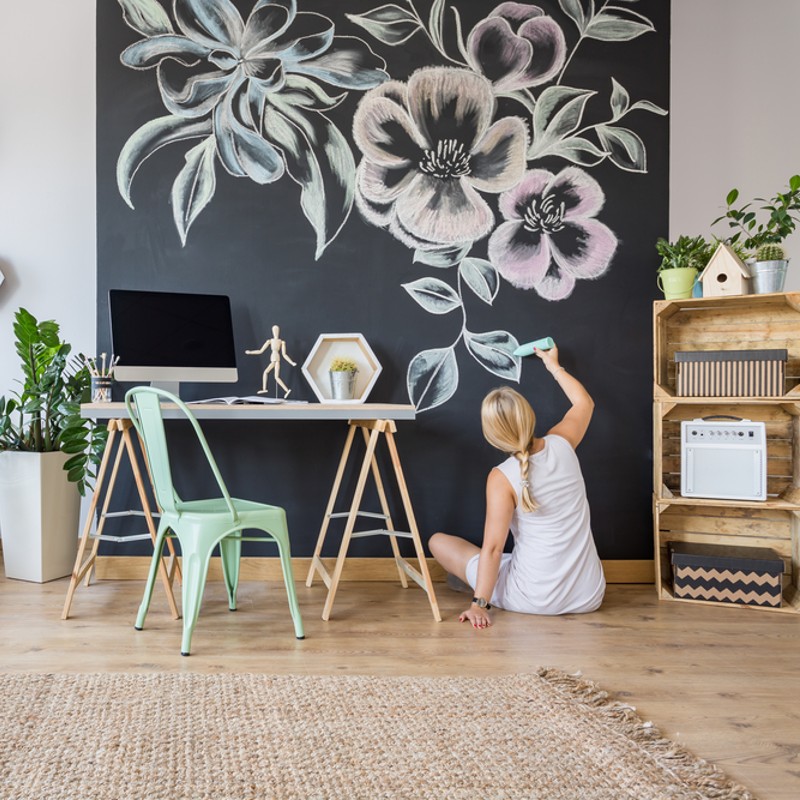 woman drawing flowers on wall at home