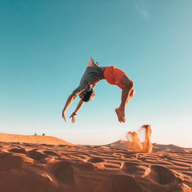 man doing backflip in the sand