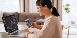 woman on phone and laptop looking at funds on screen