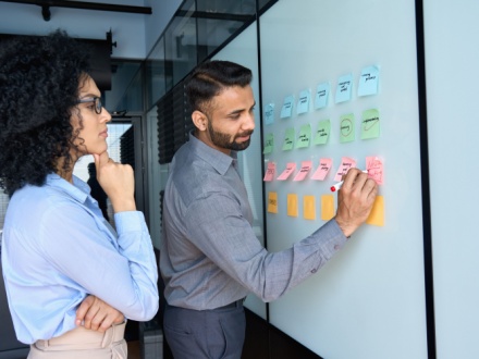 male and female office workers using whiteboard