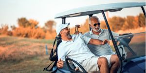 Two men in a golf buggy on a sunny golf course, laughing together