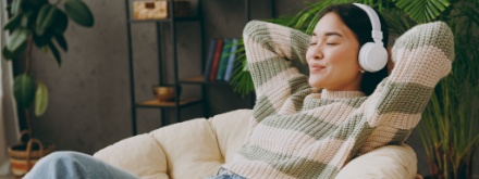 young woman in armchair listening on headphone