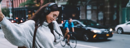Young woman on city street with headphones on