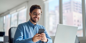 Smiling man on phone at office desk