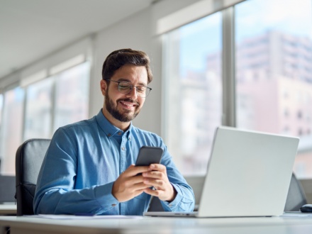 Smiling man on phone at office desk
