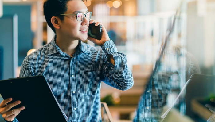 man on phone with laptop in hand
