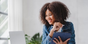 African woman at desk looking at laptop