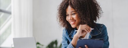 African woman at desk looking at laptop