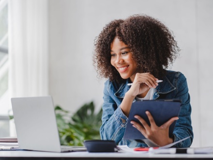 African woman at desk looking at laptop