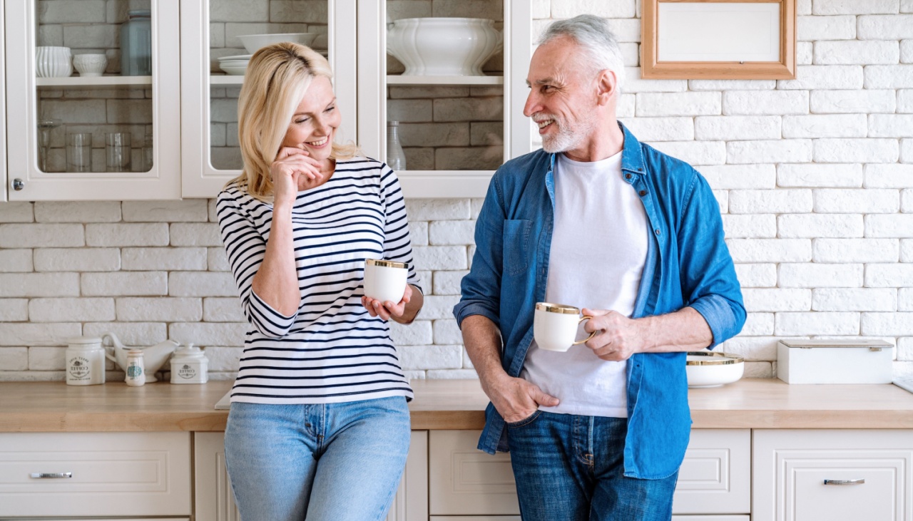 Mature woman and man spending time together standing at home kitchen drink tea