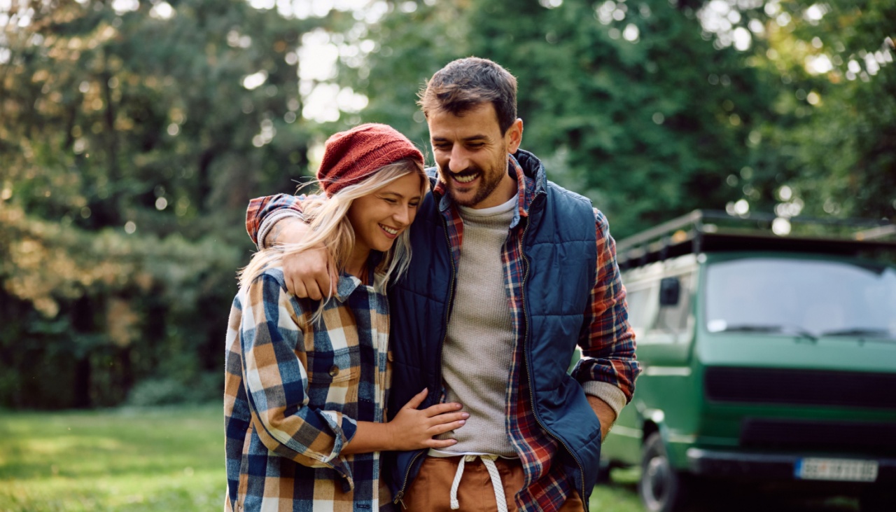 Happy couple walking embraced while camping in the forest