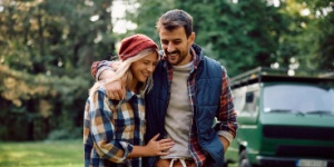 Happy couple walking embraced while camping in the forest
