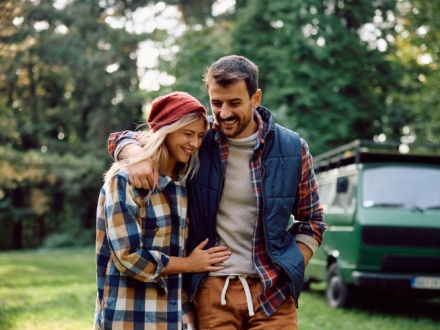 Happy couple walking embraced while camping in the forest