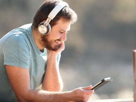 man with wireless headphones watching media content on tablet