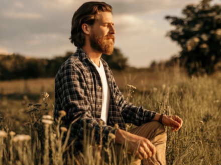 man sitting in field meditating
