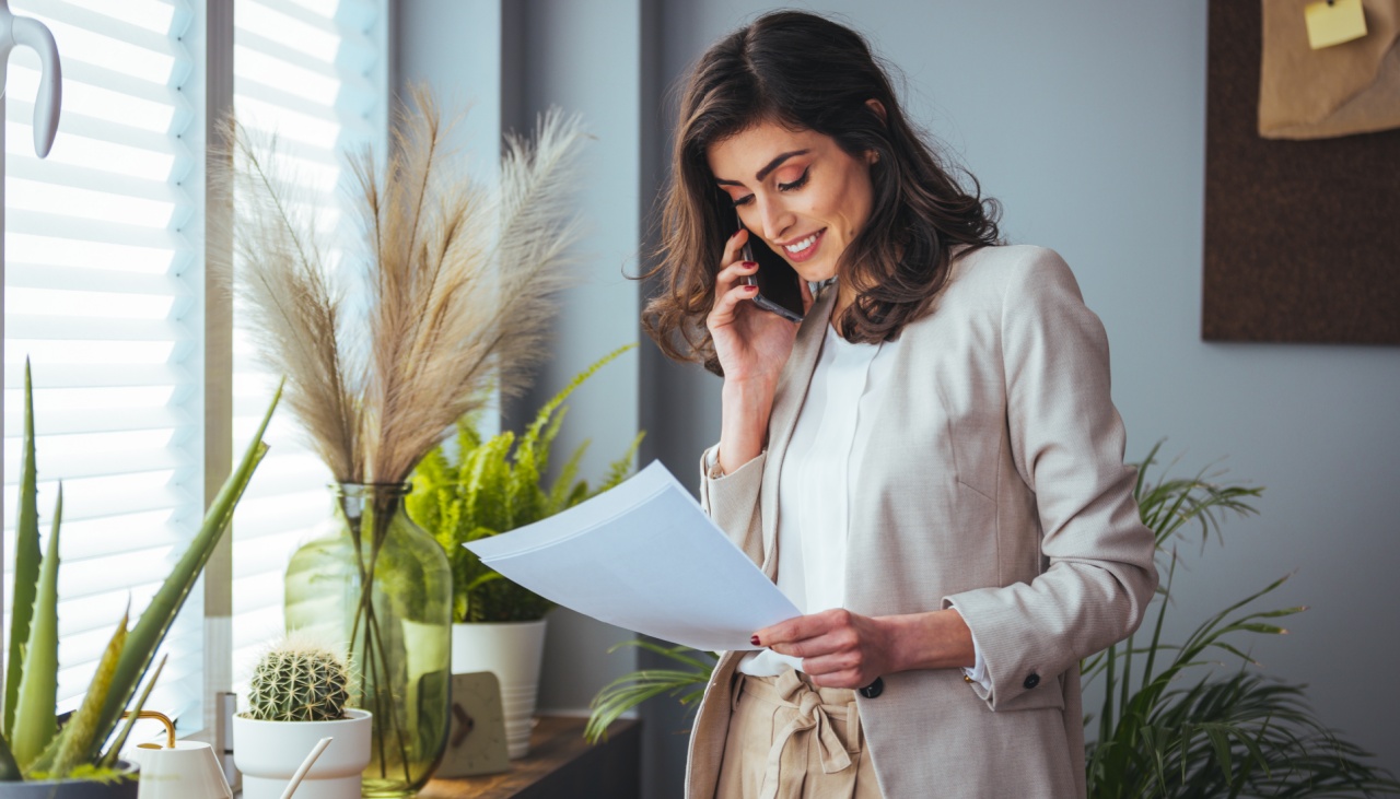 woman on phone reading paper sheet in office with plants