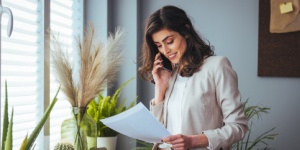 woman on phone reading paper sheet in office with plants