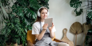 woman at listening to a podcast with plants in the background