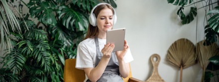 woman at listening to a podcast with plants in the background