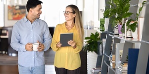 Couple of happy young office friends walking in co-working space