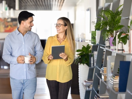 Couple of happy young office friends walking in co-working space