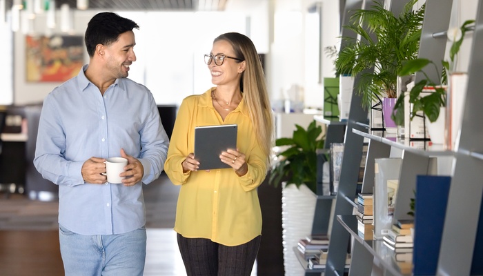 Couple of happy young office friends walking in co-working space