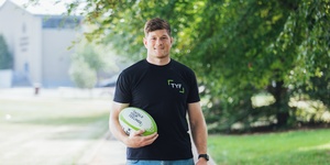 Rugby player Jack O’Donoghue holding a rugby ball with Tackle your feelings written on it