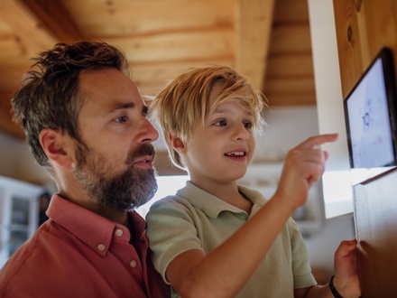 Father and son at home keying in information on home energy system tablet