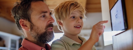 Father and son at home keying in information on home energy system tablet