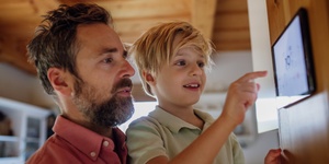 Father and son at home keying in information on home energy system tablet