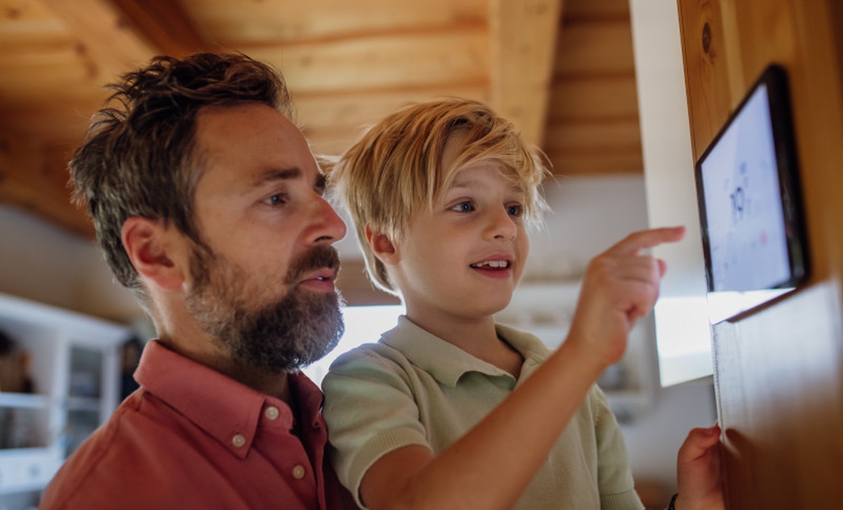 Father and son at home keying in information on home energy system tablet