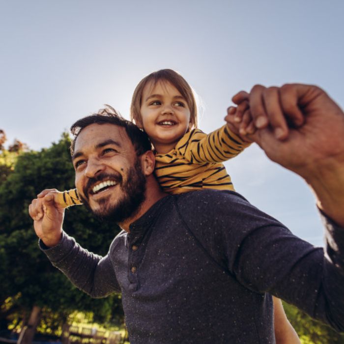 Young smiling bearded dad with his young daughter on his back