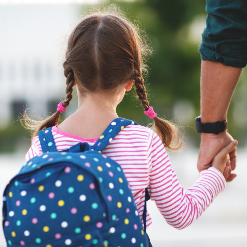 child holding hands with father going to school
