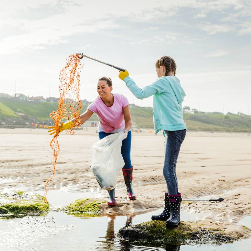 mother and daughter collecting rubbish from beach