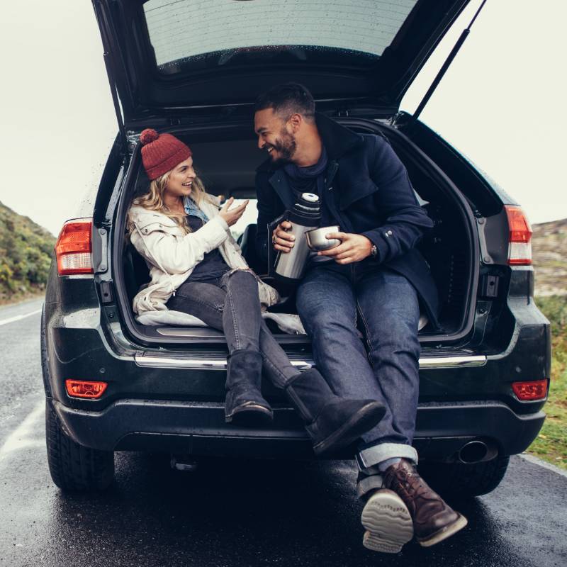 A couple sitting on the back of a car