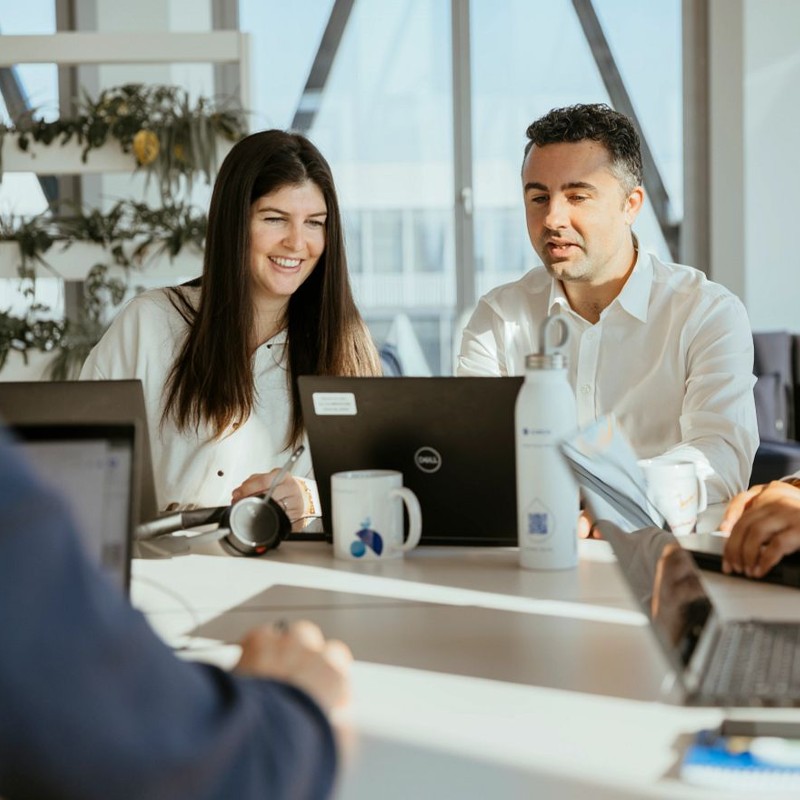 Male and female business colleagues at board room table with laptop