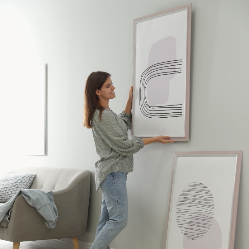 woman hanging pictures in sitting room