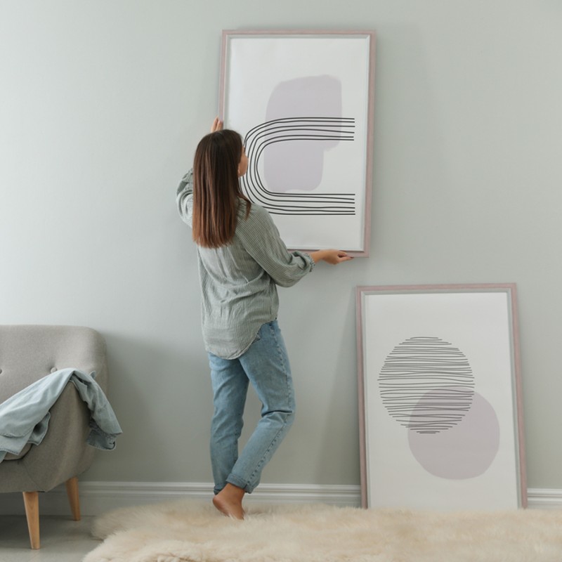 woman hanging pictures on wall at home
