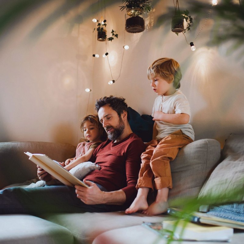 Father reading on sofa with two small children a boy and a girl
