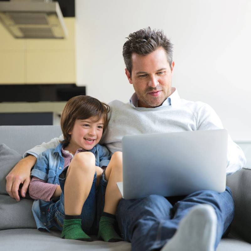Dad and son on the sofa looking at a laptop