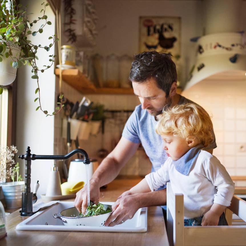 father and son washing vegetables at kitchen sink