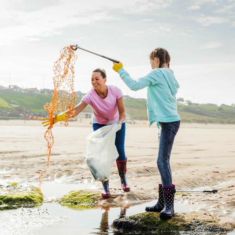 Beach clean up - a lady and girl cleaning a beach