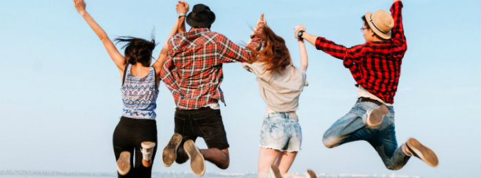 a group of young people holding hands jumping in the air