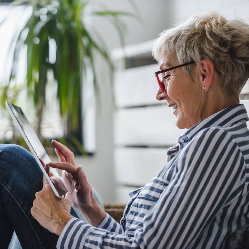 Middle aged woman using digital tablet while sitting on floor